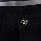 Close-up of black denim pants button with round metal decorative emblem