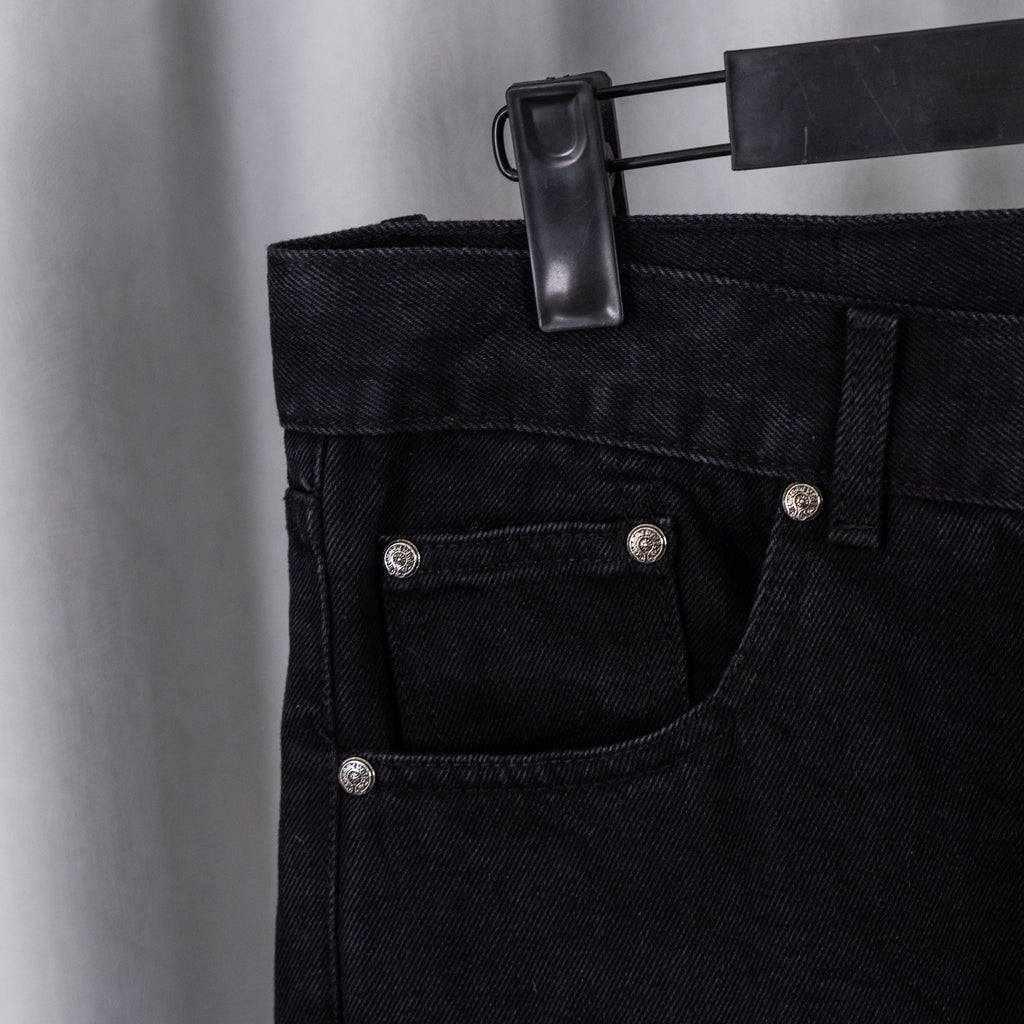 Black denim pants front with button fly, pockets, and metal rivets