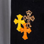 Black denim pants with yellow and orange cross patches on the front