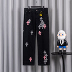 Black denim pants with pink and checkered cross patches, front view.