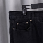 Black denim pants with buttoned front and pocket detailing.