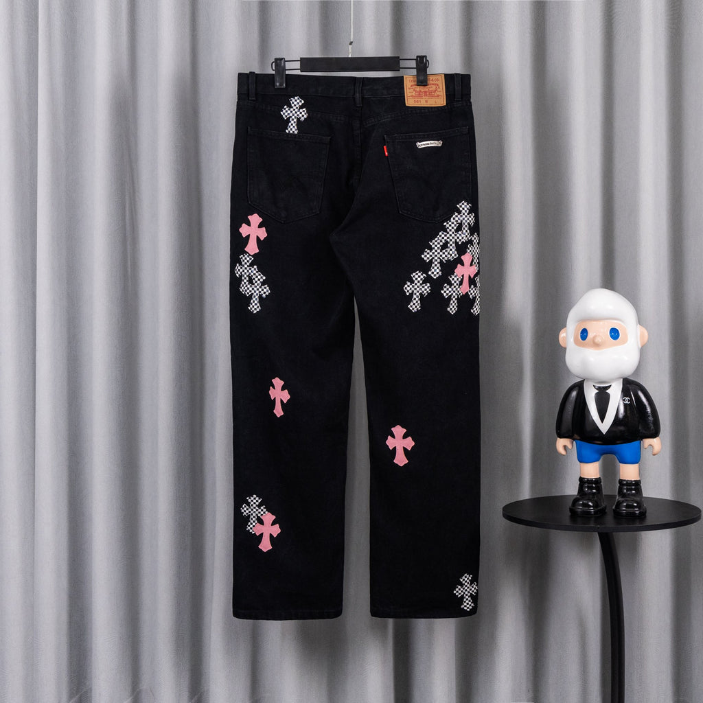 Black denim pants with pink and checkered cross patches, back view.