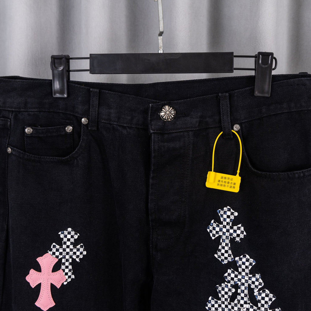 Black denim pants with cross patch graphics and belt-loop waistband.