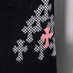 Black denim pants with multiple checkered cross patches and pink cross accents.