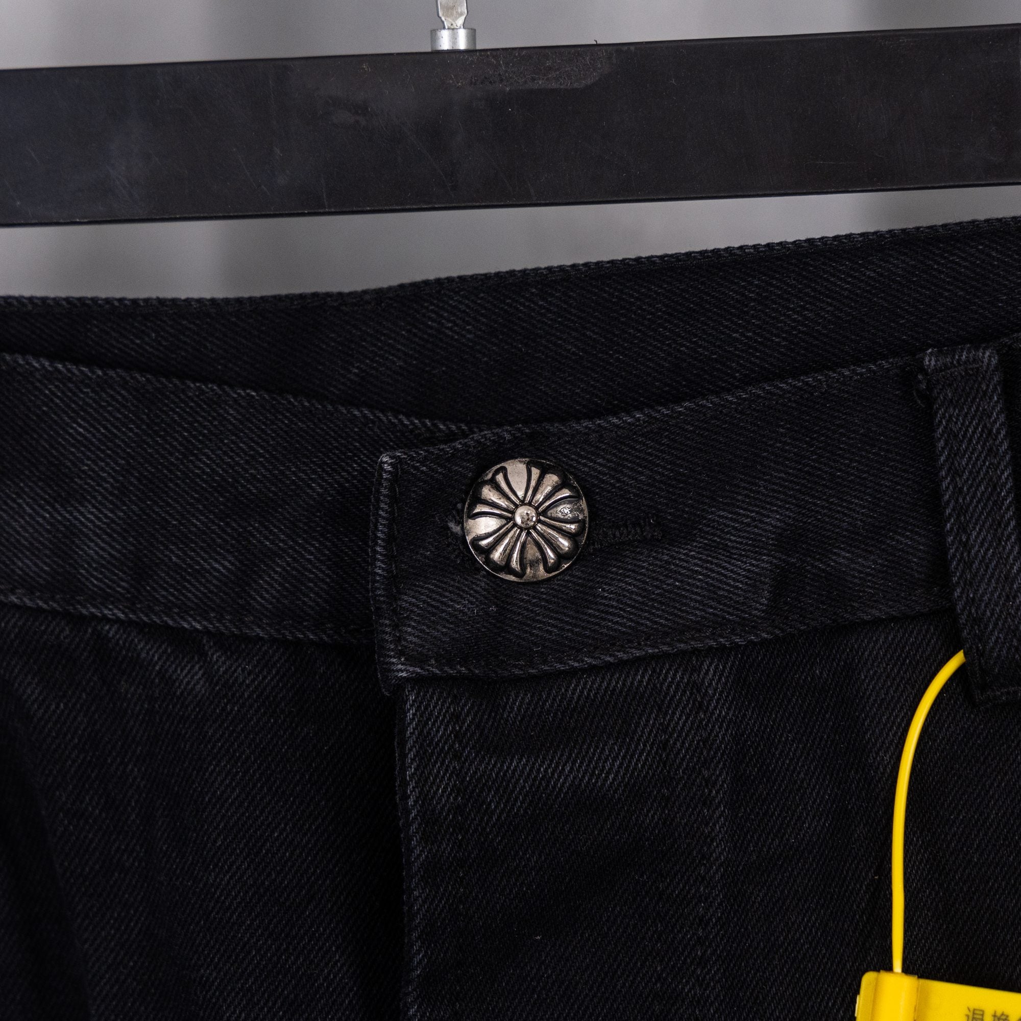 Black denim pants with metal button and belt-loop detail at waistband