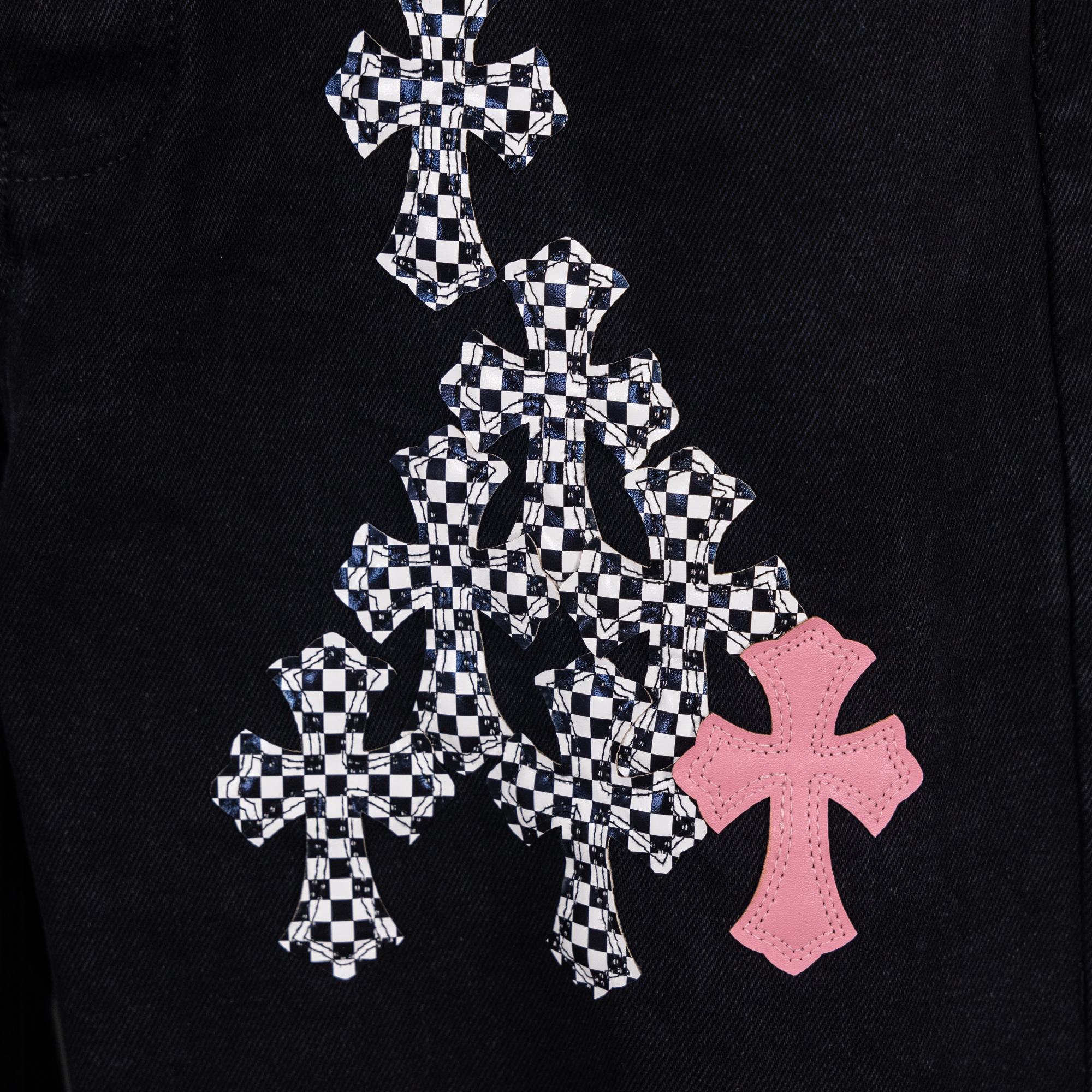 Black denim pants with large checkerboard cross graphic and pink cross emblem