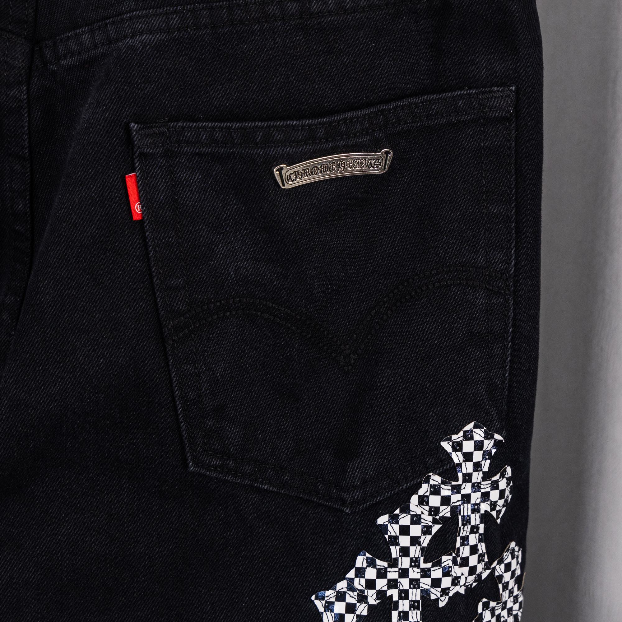 Black denim pants; logo patch and checkerboard cross graphic near front pocket