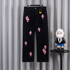 Dark denim pants with pink cross patches, button fly and belt loops.
