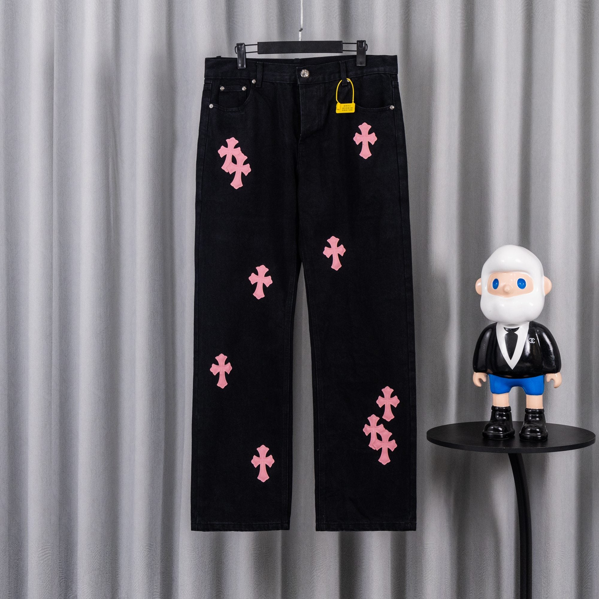 Dark denim pants with pink cross patches, button fly and belt loops.