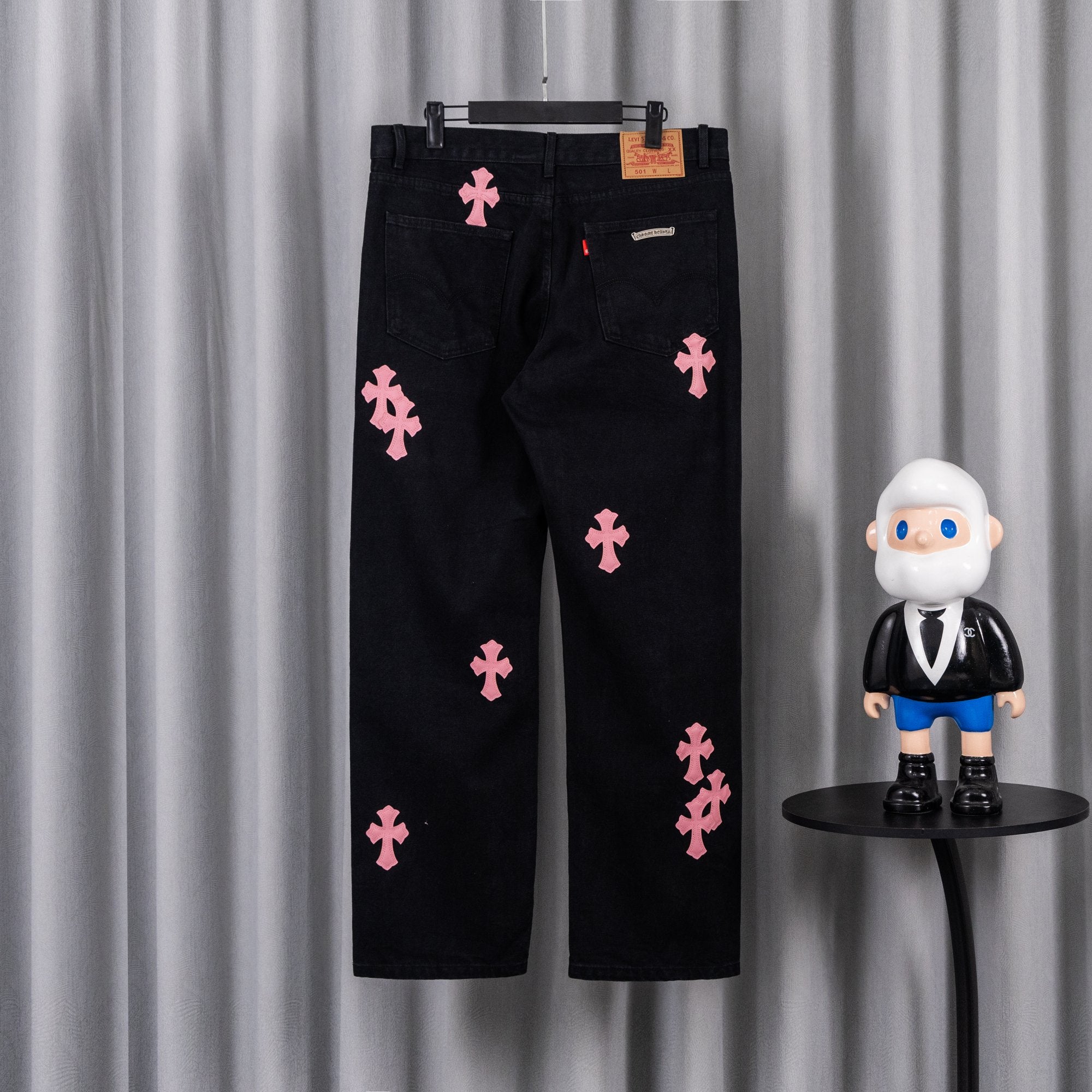 Dark denim pants with scattered pink cross embroidery, zip fly and front pockets.
