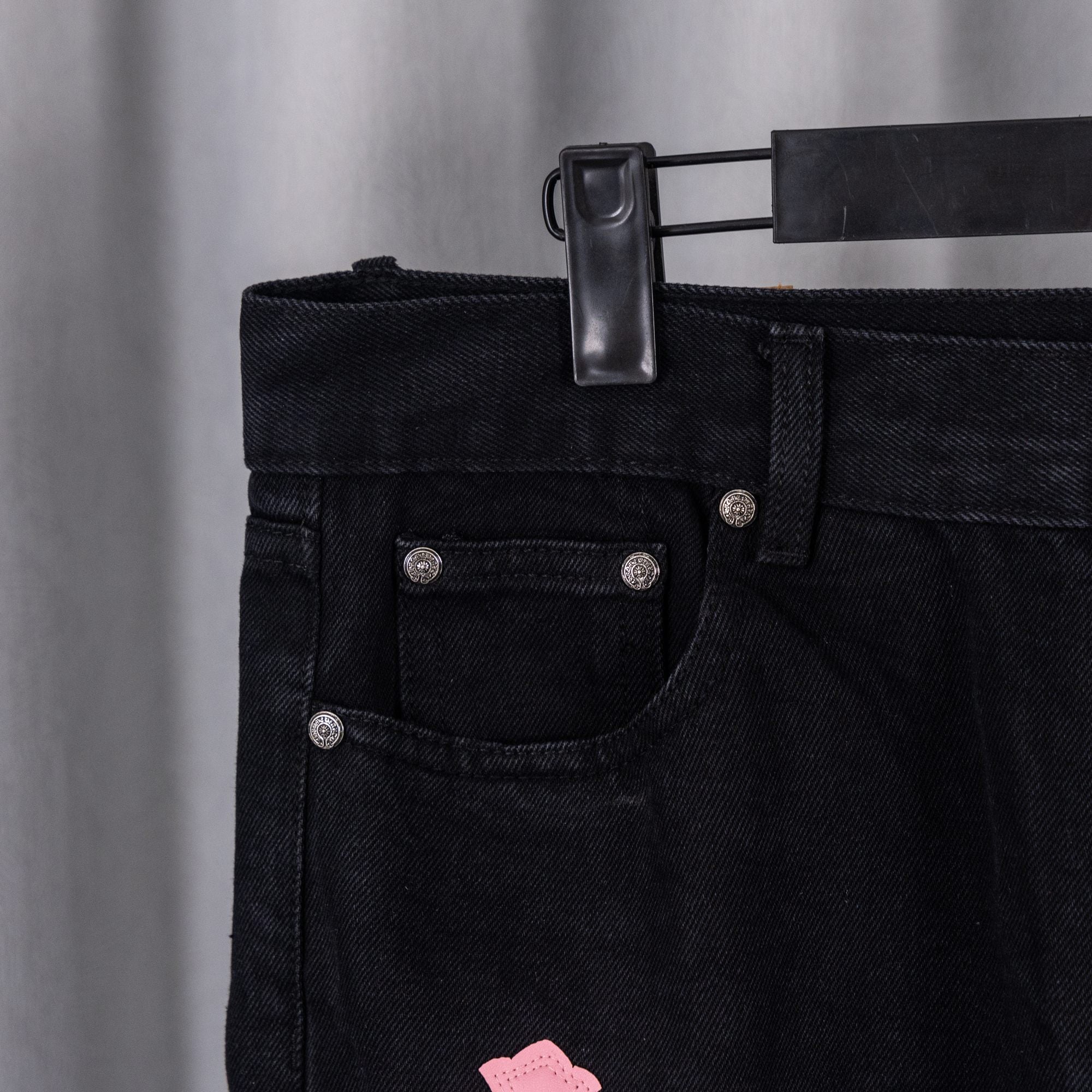 Dark denim jean pocket and waistband with metal rivets and belt loop detail.