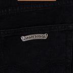 Metal logo patch on dark denim pocket seam, small rectangular tag.