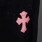 Pink cross applique on dark denim near pocket seam.