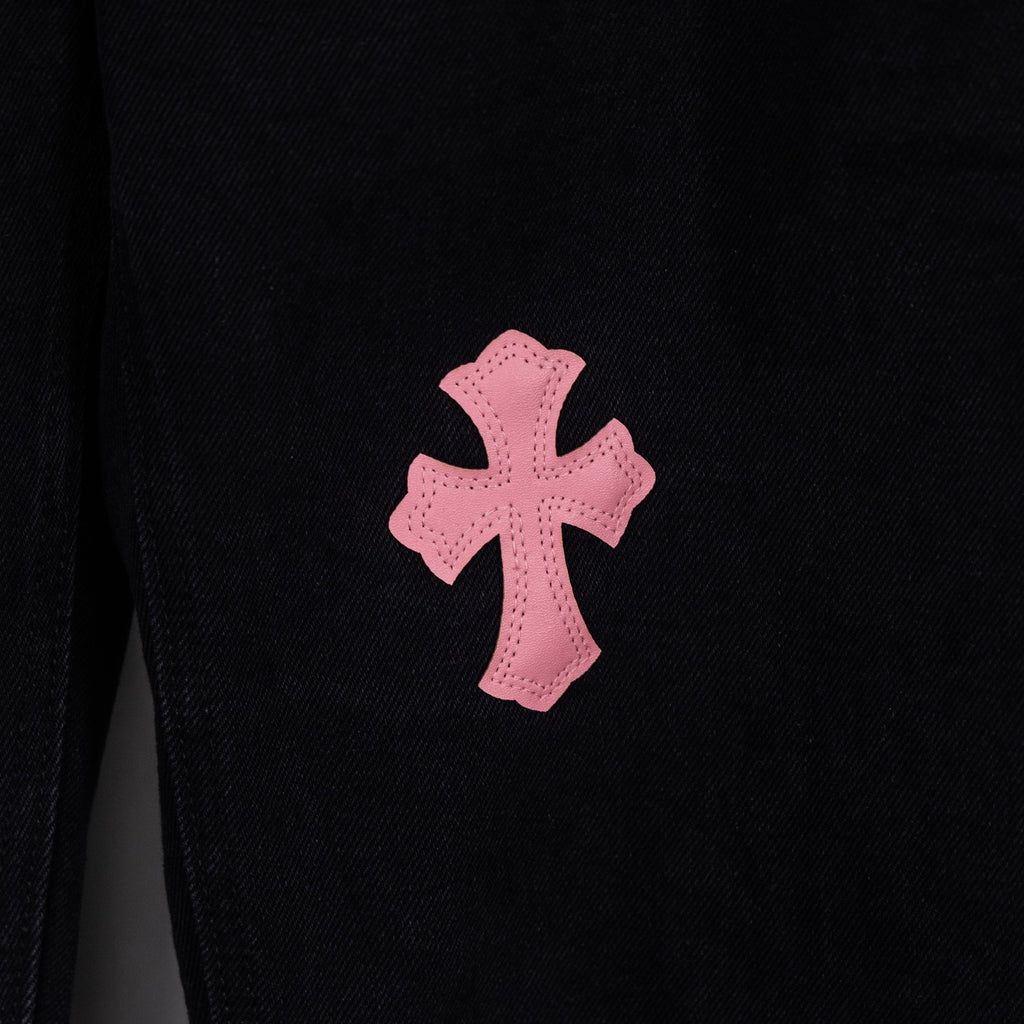 Black denim pants with large pink cross patch on leg