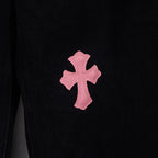 Black denim pants with large pink cross patch on leg