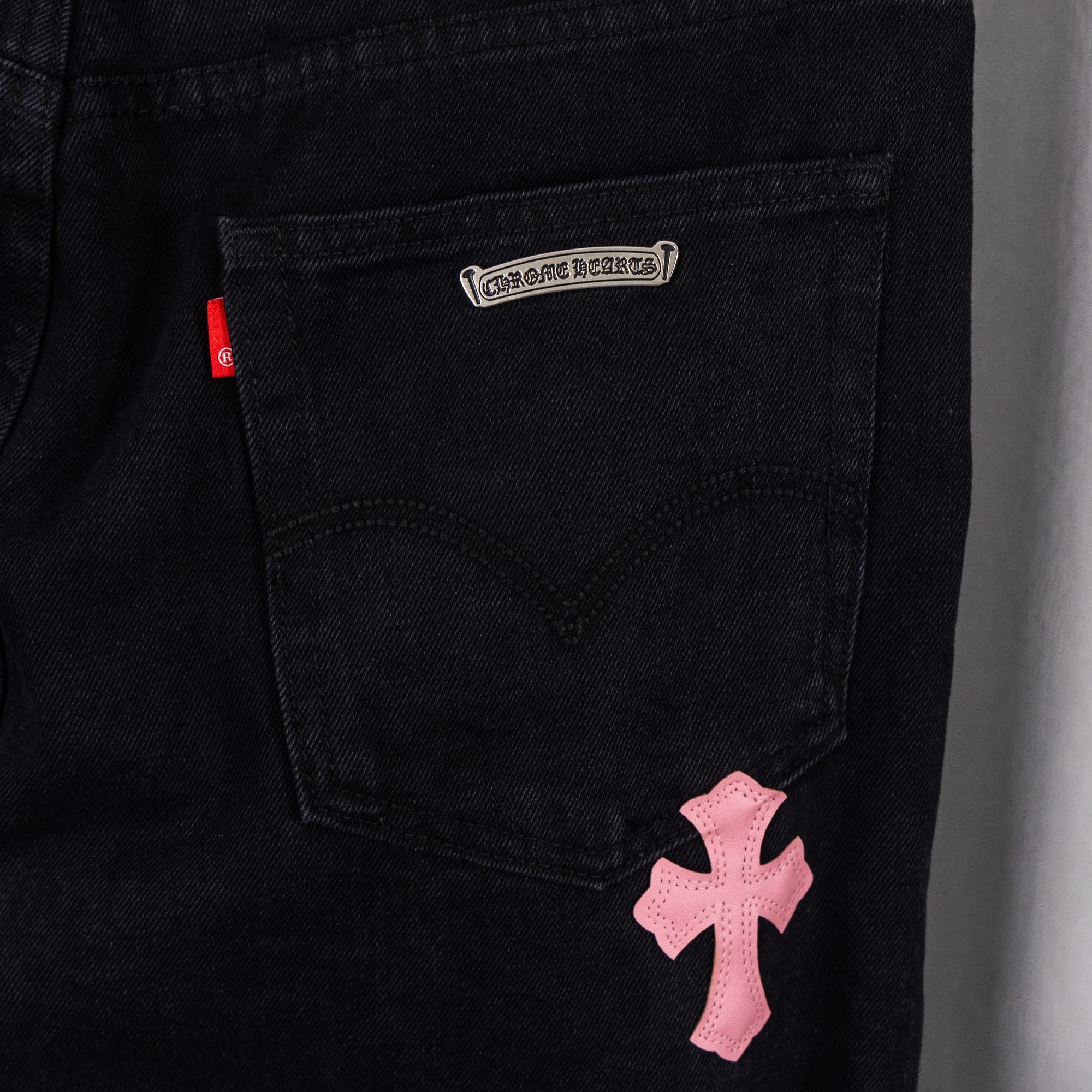 Black denim pants with pink cross patch on front pocket