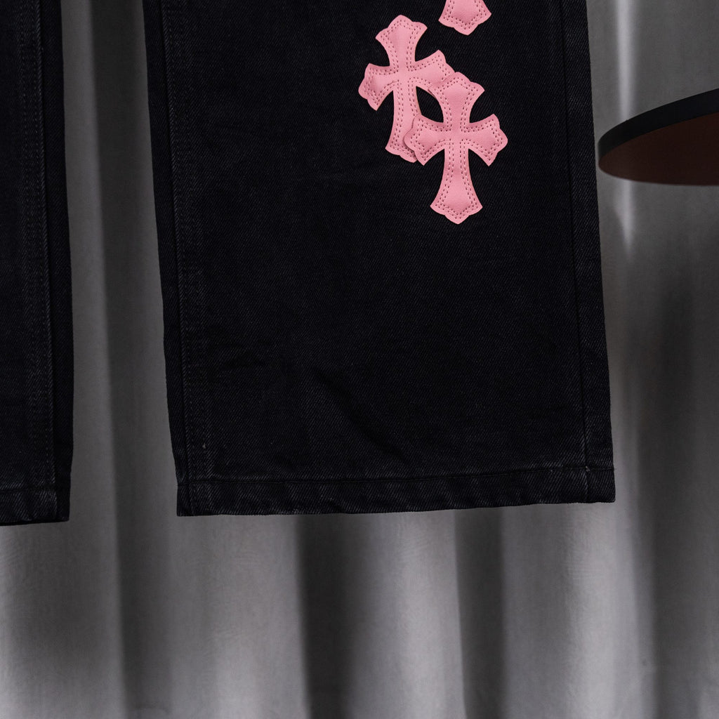 Black denim pants with pink cross patch on thigh