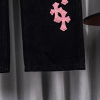 Black denim pants with pink cross patch on thigh