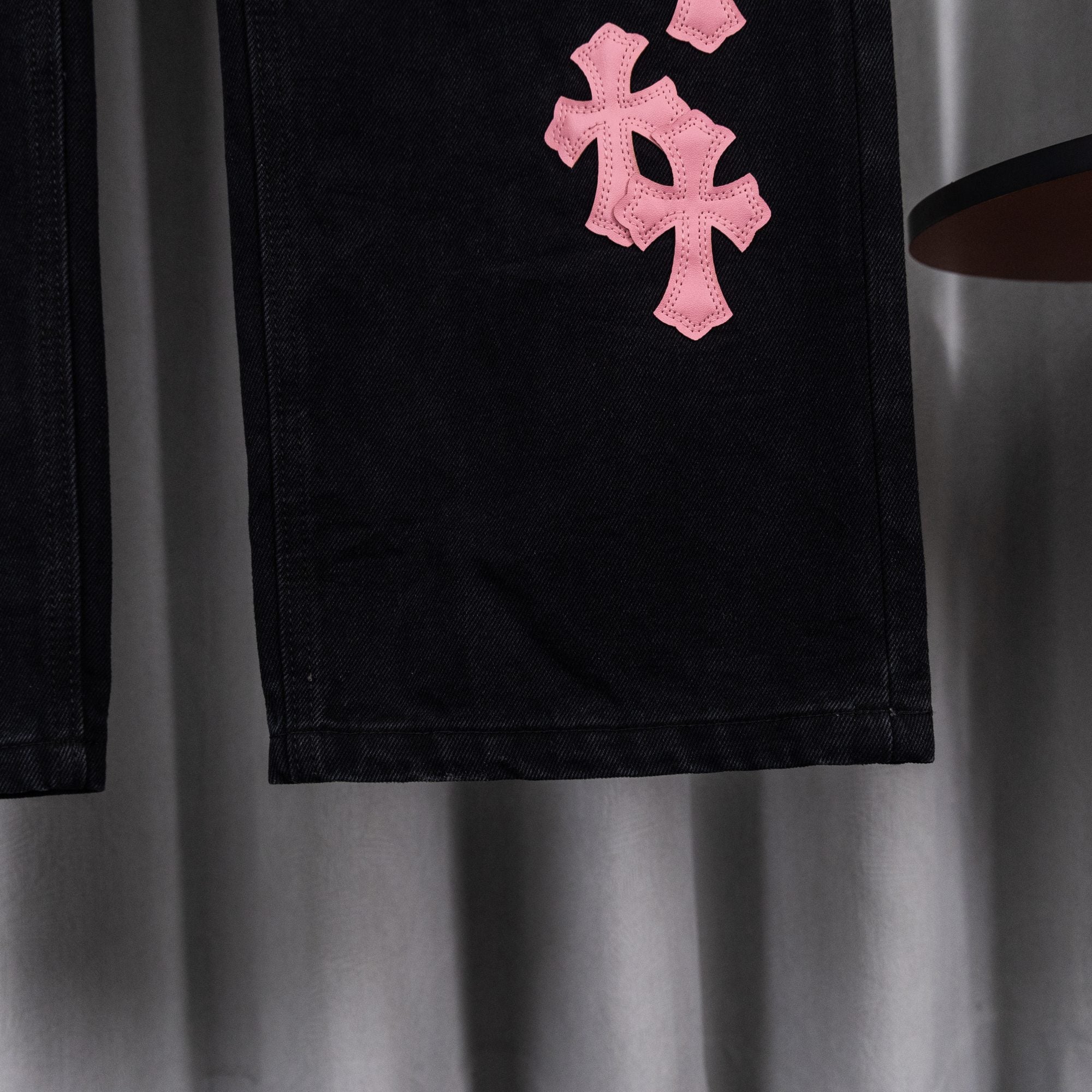 Black denim pants with pink cross patch on thigh