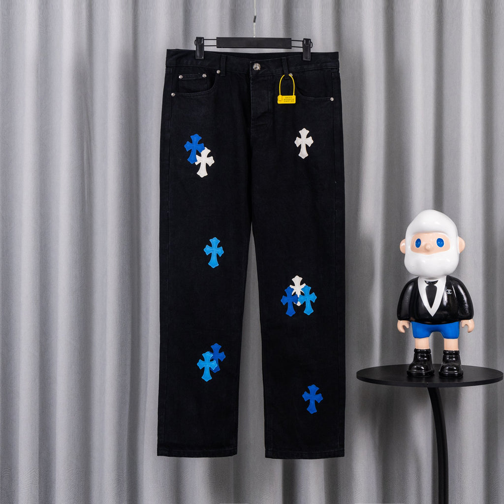 Black denim pants with blue and white cross appliques, five-pocket style.