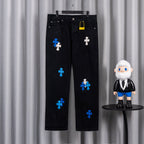 Black denim pants with blue and white cross appliques, five-pocket style.