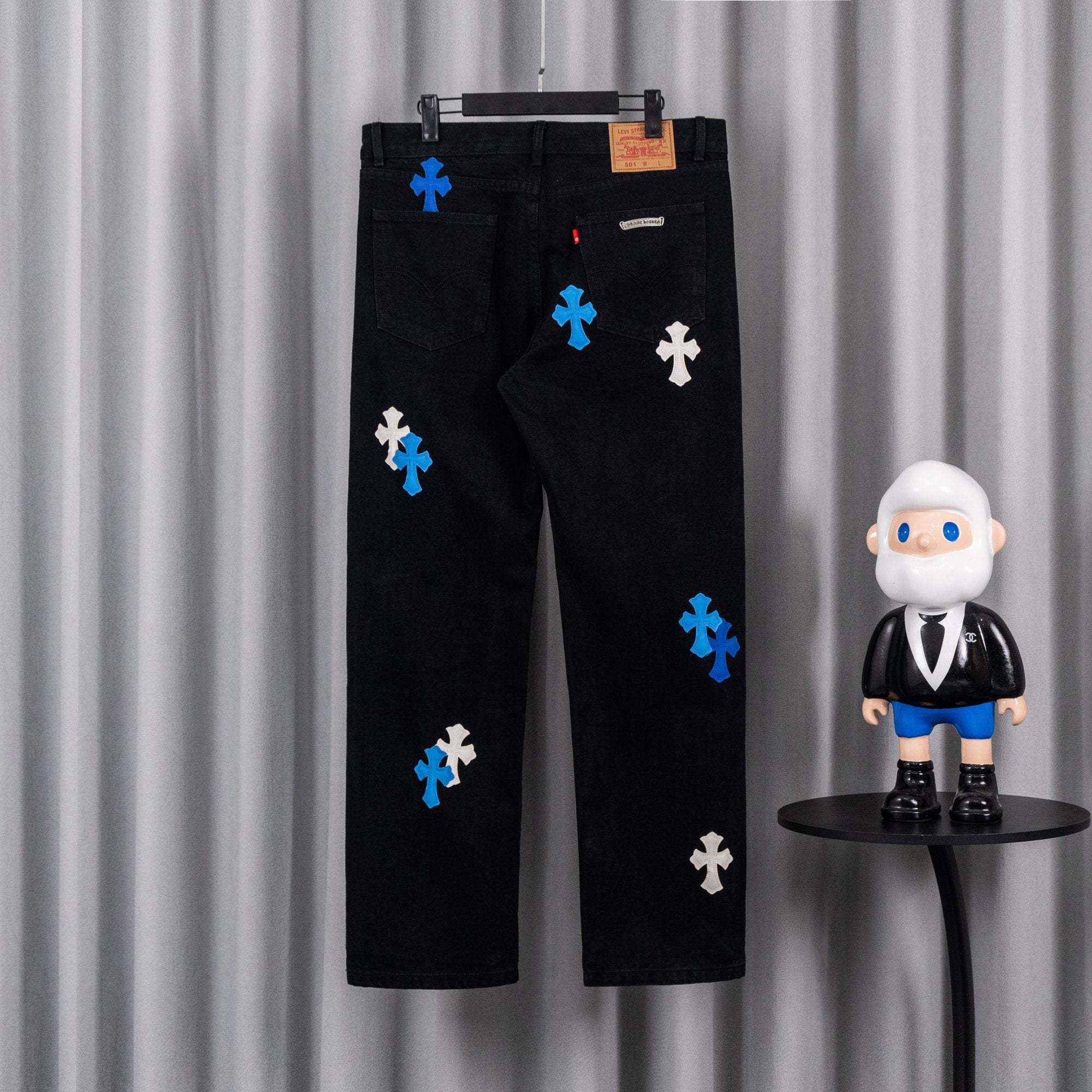 Black denim pants with blue and white cross appliques, front patch pockets.