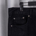 Black denim pants waistband with belt loops and buttoned front pocket.