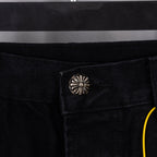 Black denim pants with snap coin pocket and belt loop, close-up detail.