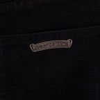 Black denim pants with metal-look logo tag near pocket seam