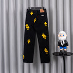 Black denim pants with yellow cross patches and front zip, belt loops, tag