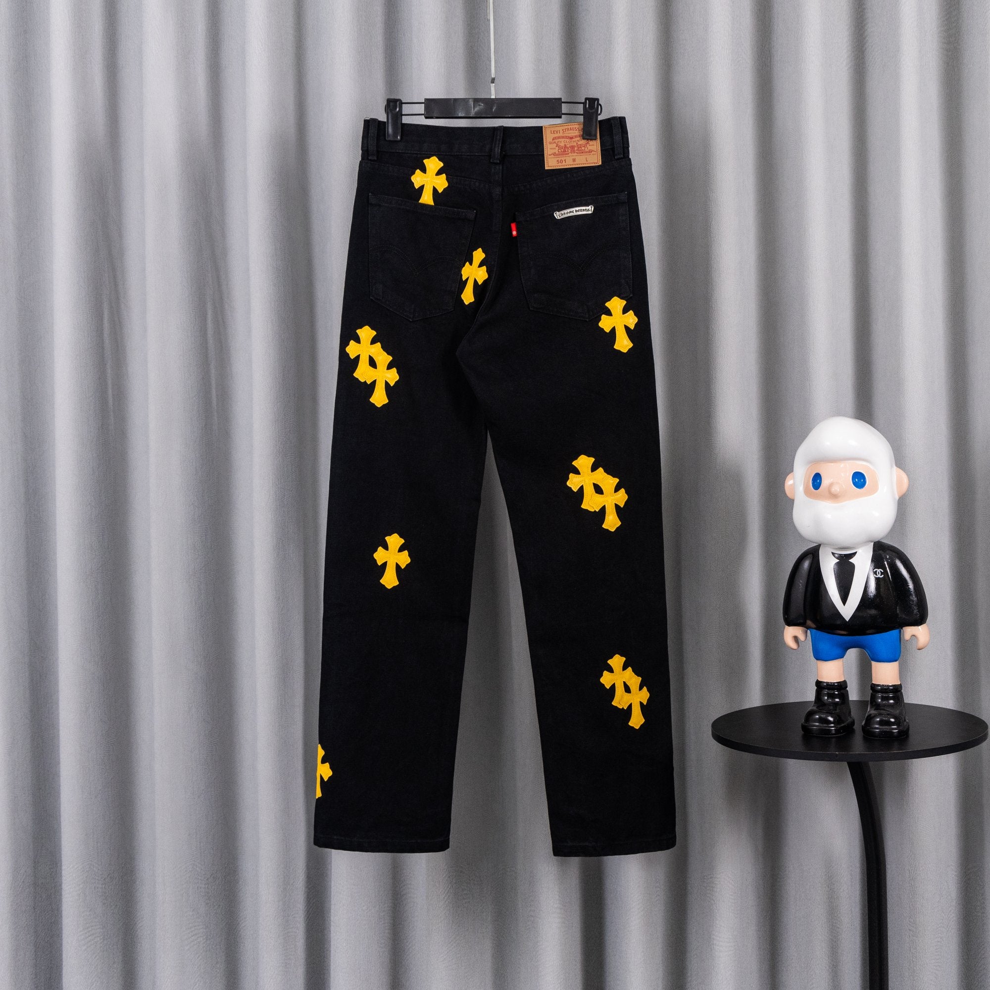 Black denim pants with yellow cross patches and front zip, belt loops, tag
