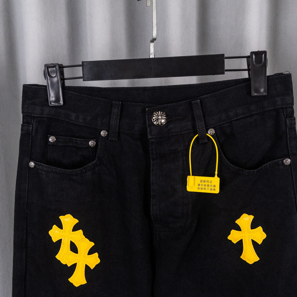 Black denim pants front with metal button, pockets, yellow cross patches, hang tag