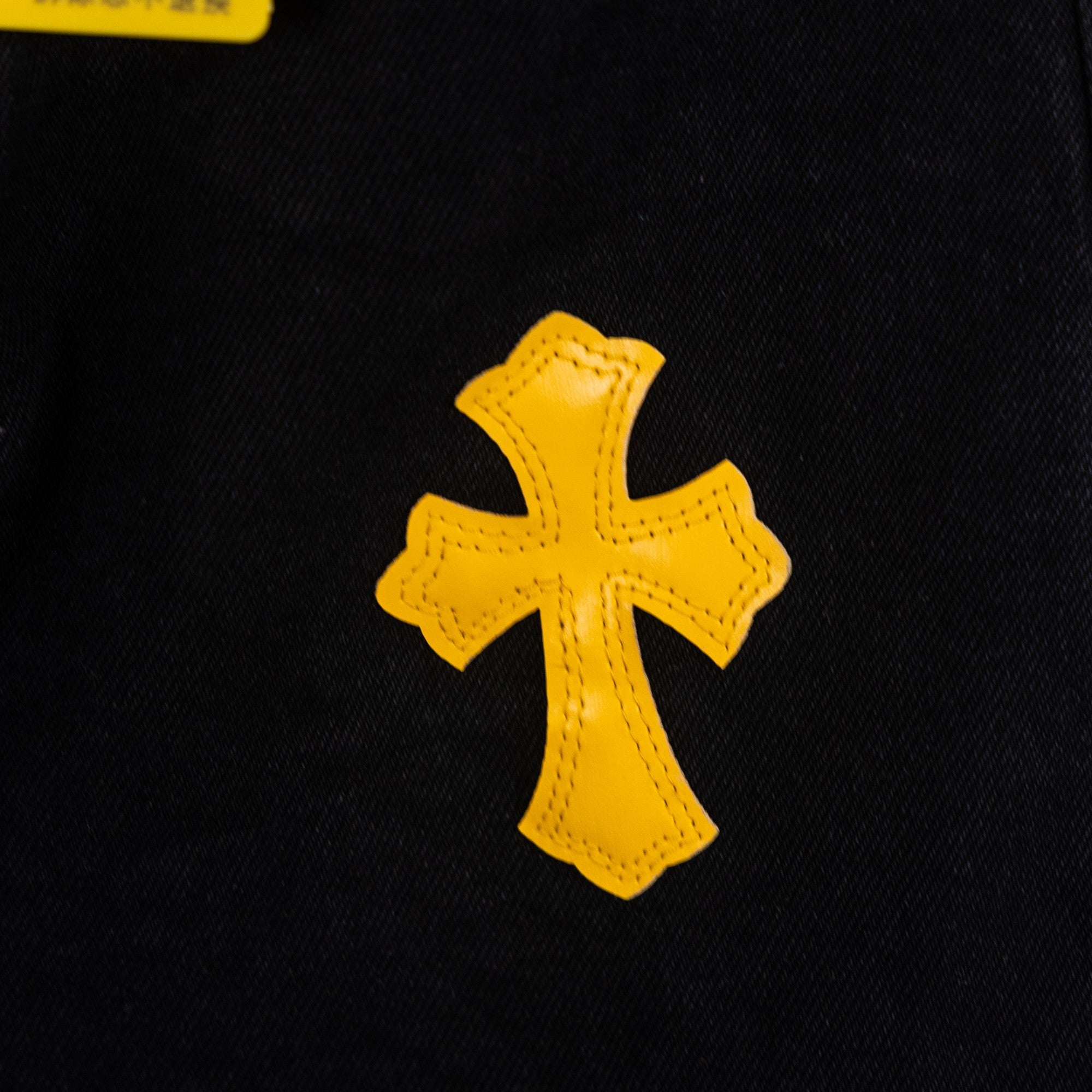 Yellow cross applique patch on black denim fabric