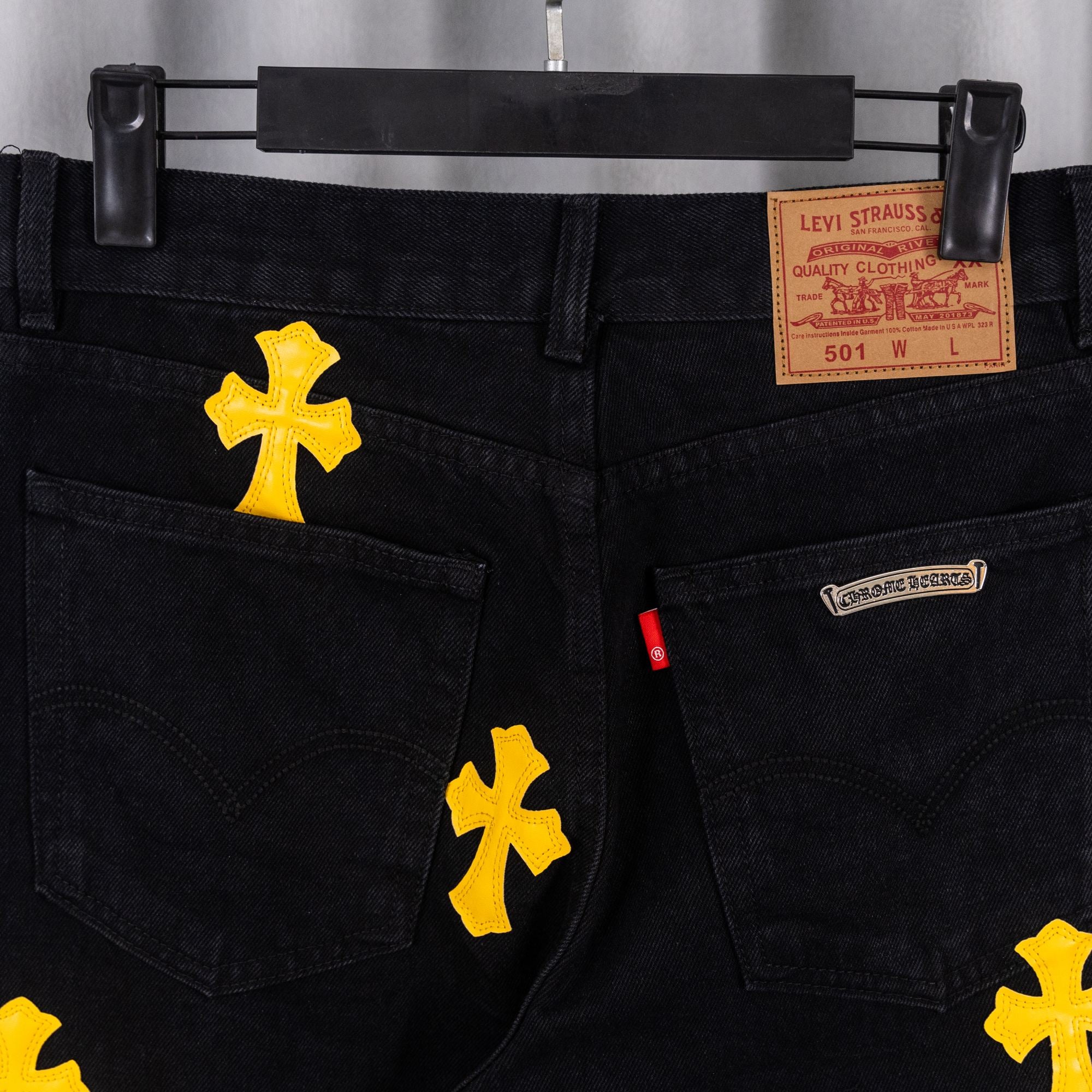 Black denim pants with Levi Strauss quality label and yellow cross patches