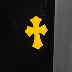 Black denim pants with yellow cross applique on leg