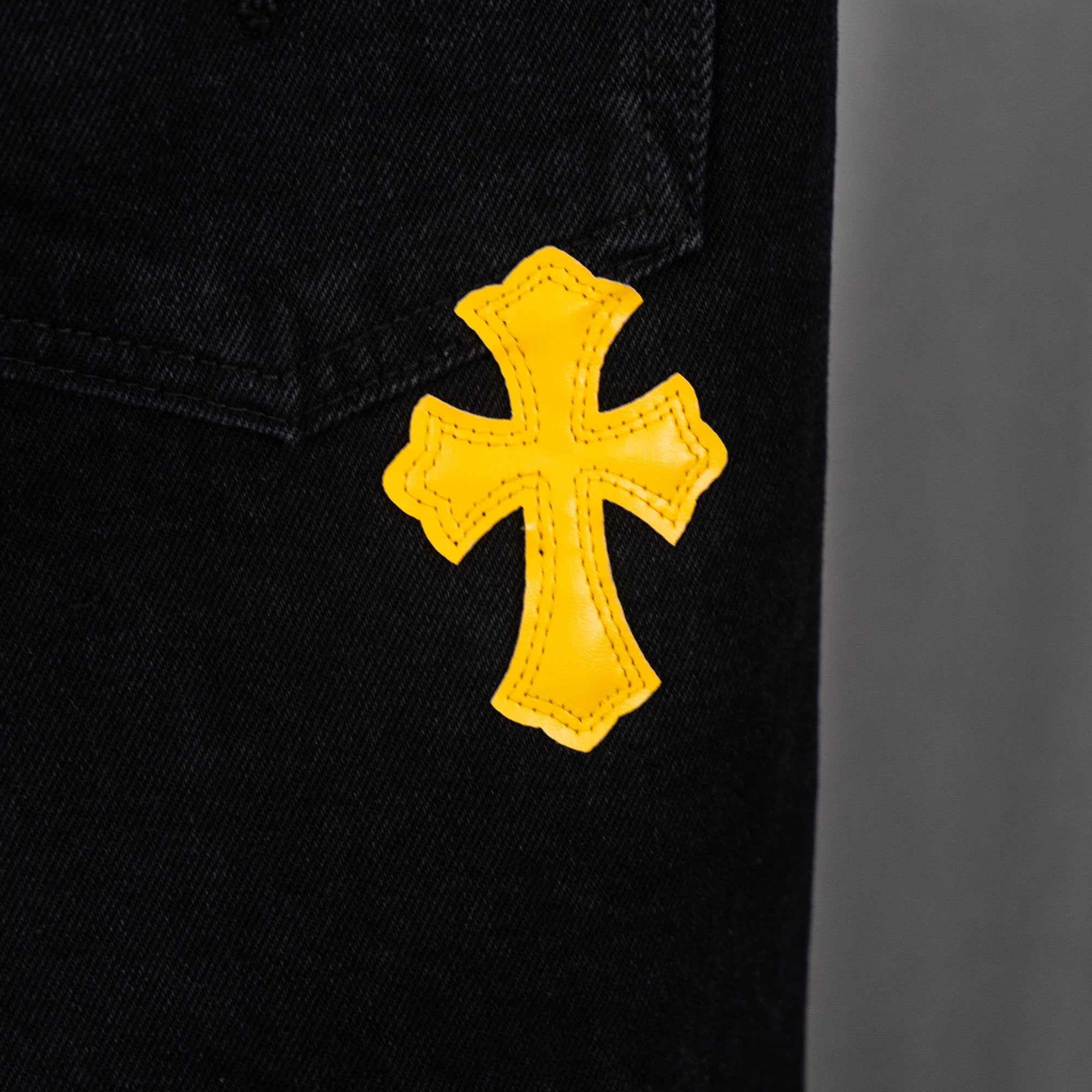 Black denim pants with yellow cross applique on leg