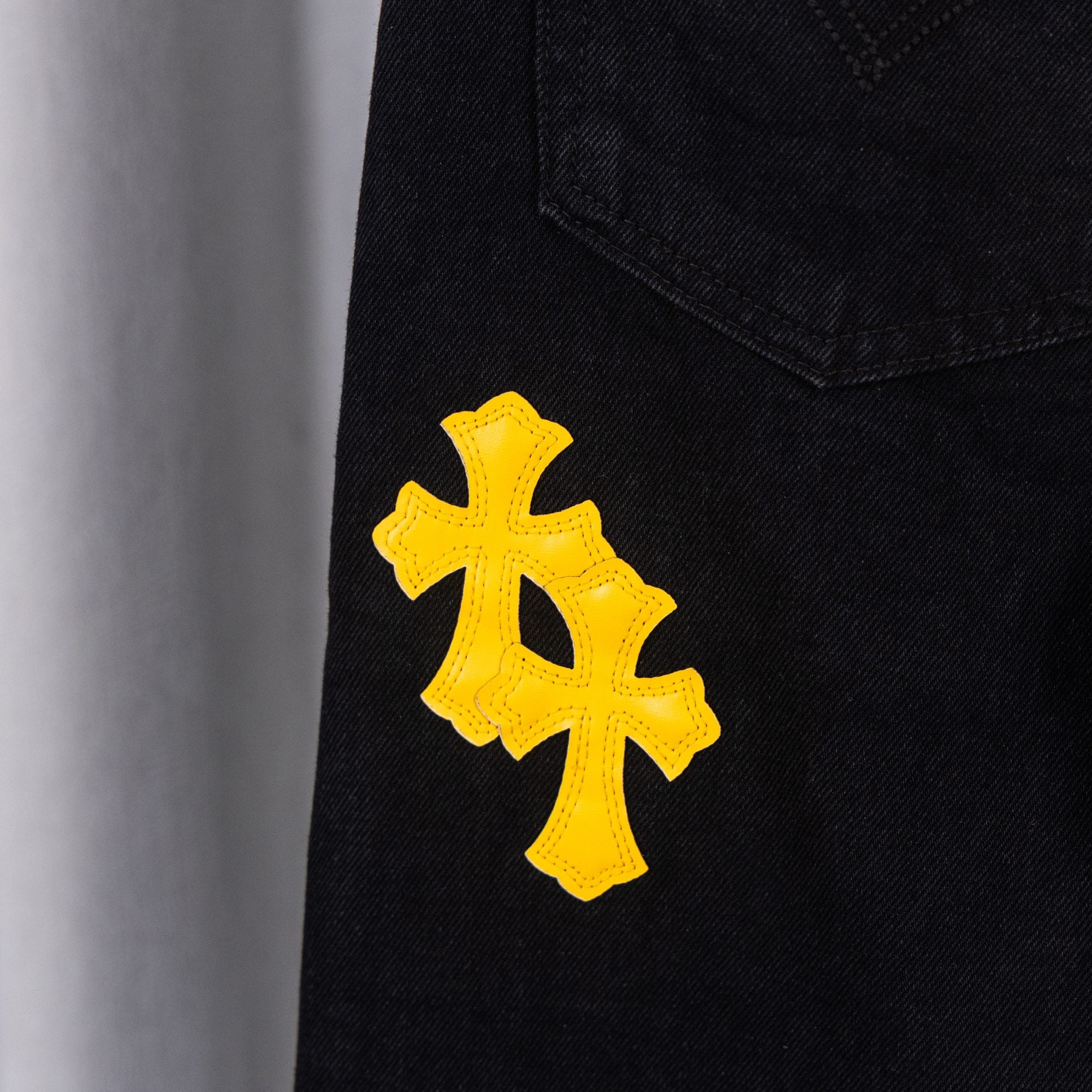 Black denim pants with yellow cross patch on side
