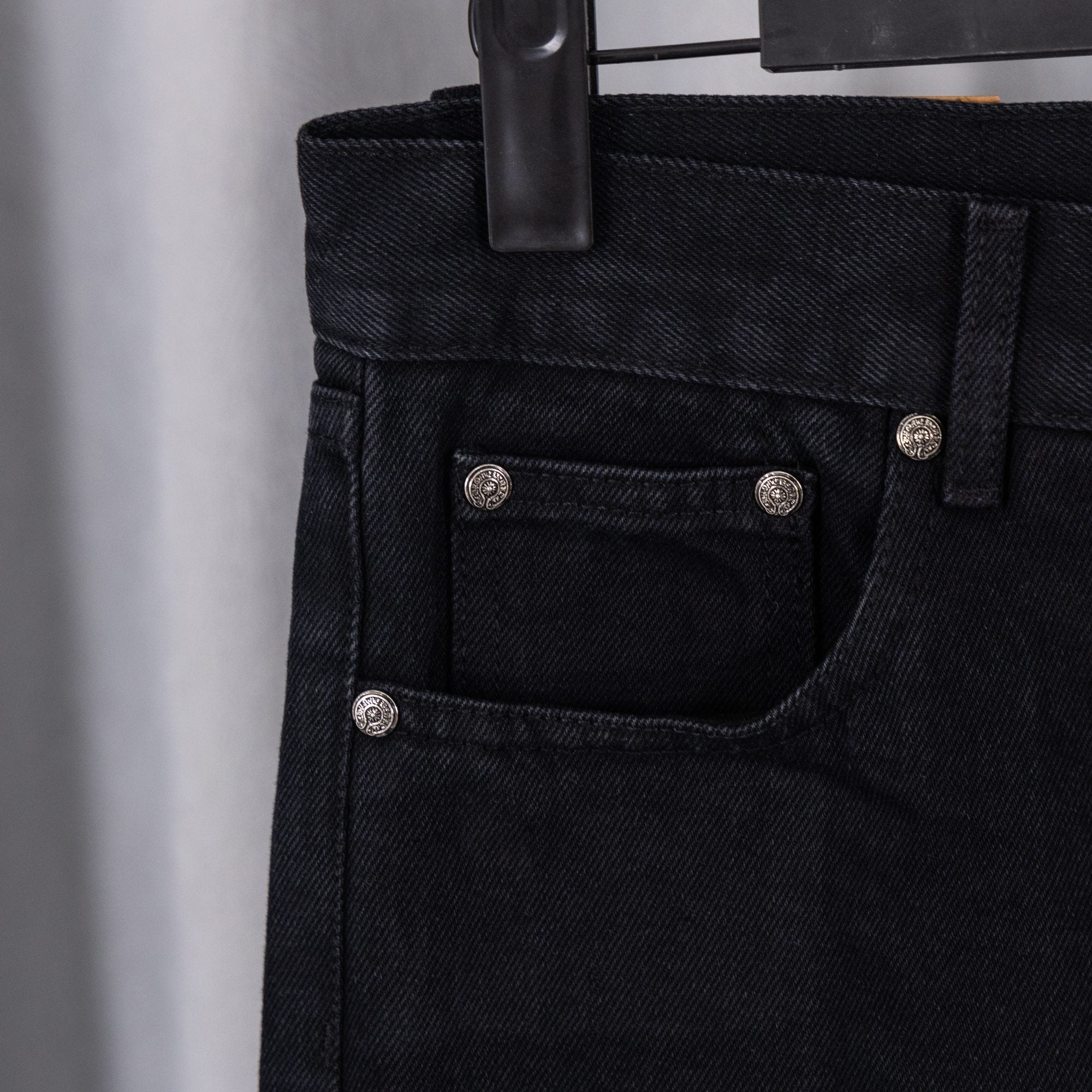 Black denim pants with front pocket and buttoned waistband detail