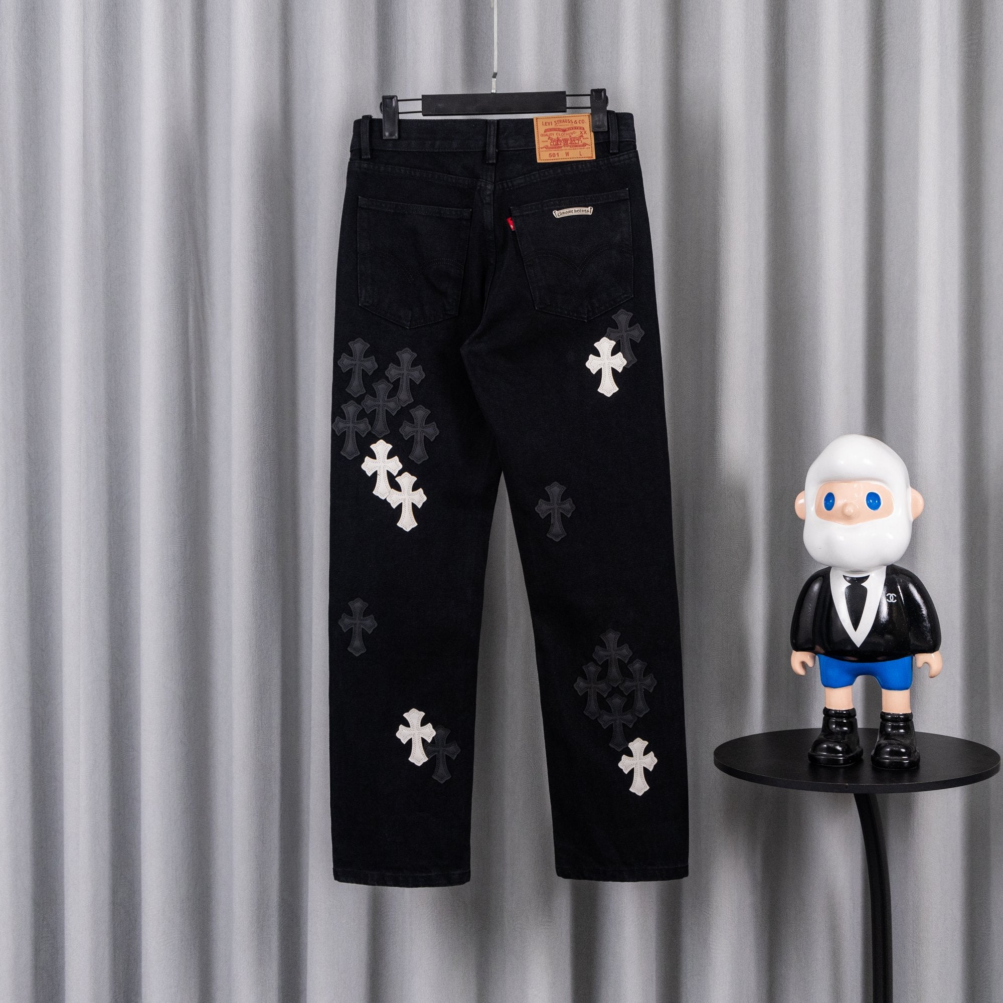 Black pants with dark cross patches, back view on hanger