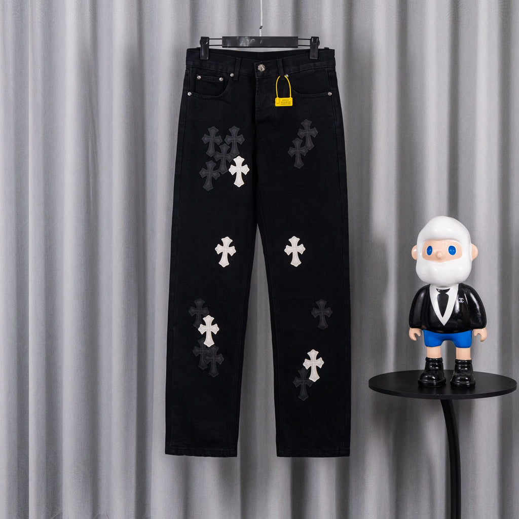 Black pants with embroidered white cross patches, front view on hanger