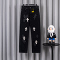 Black pants with embroidered white cross patches, front view on hanger