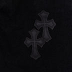 Black denim pants with dark cross patches along the leg