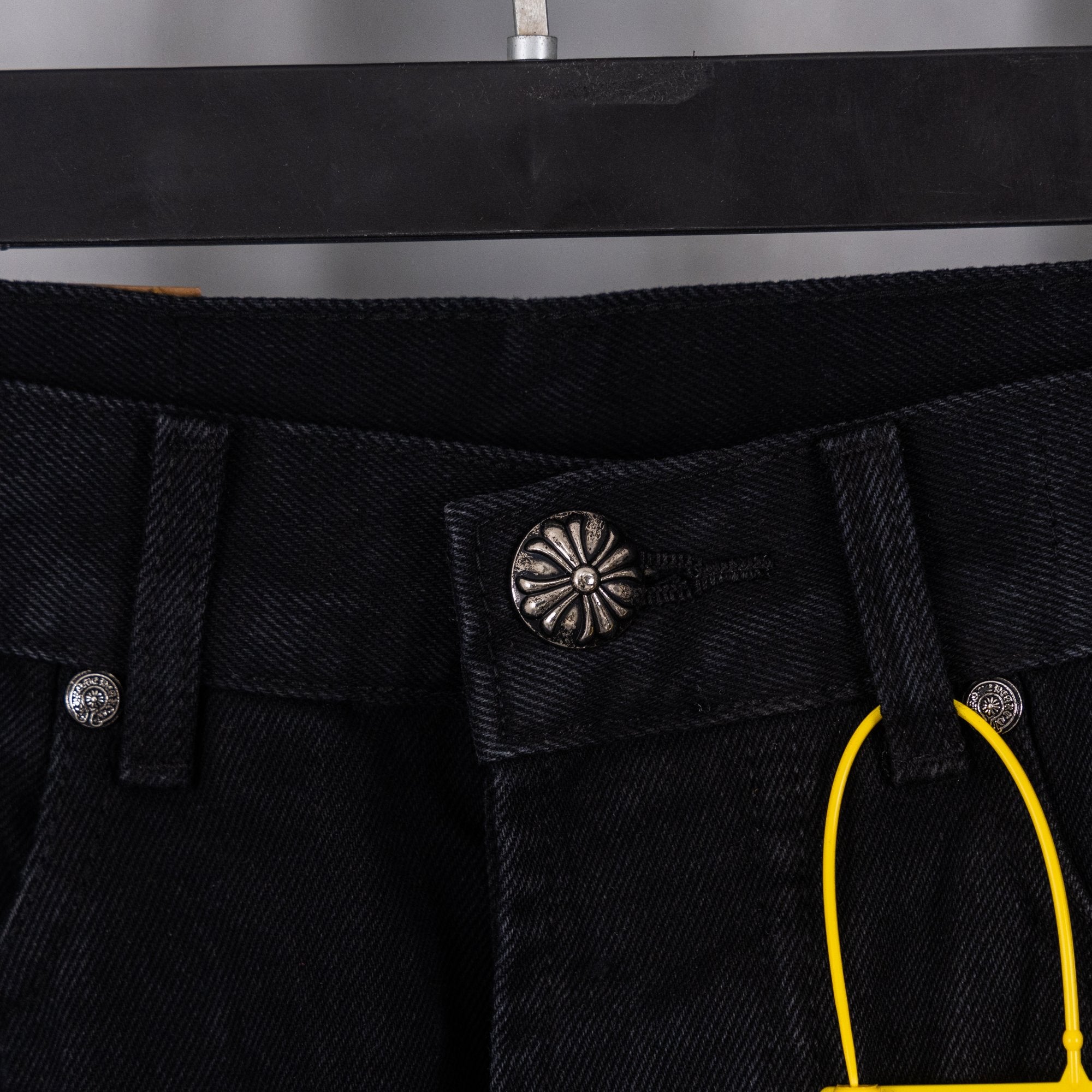Black denim pants with coin pocket, decorative center button, and belt loops