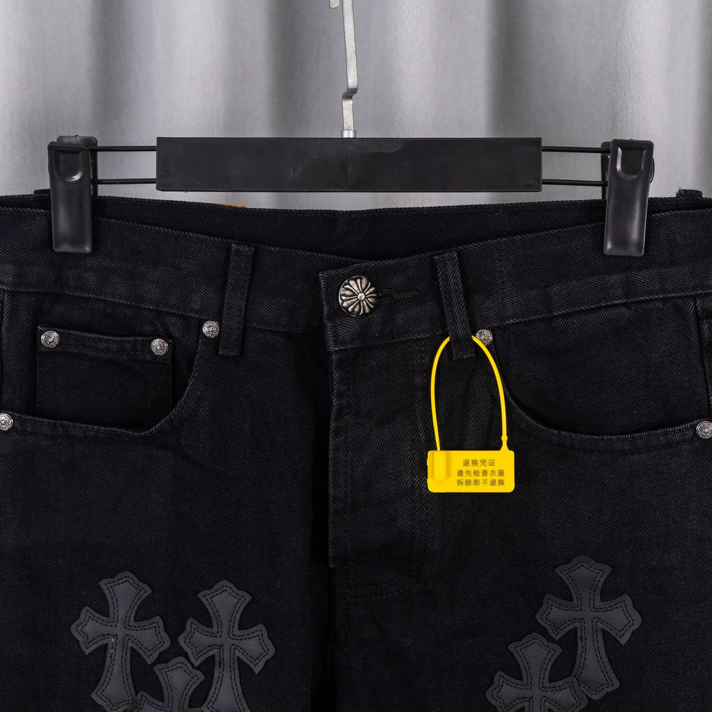 Black denim pants with cross patches, waistband front view, with yellow tag