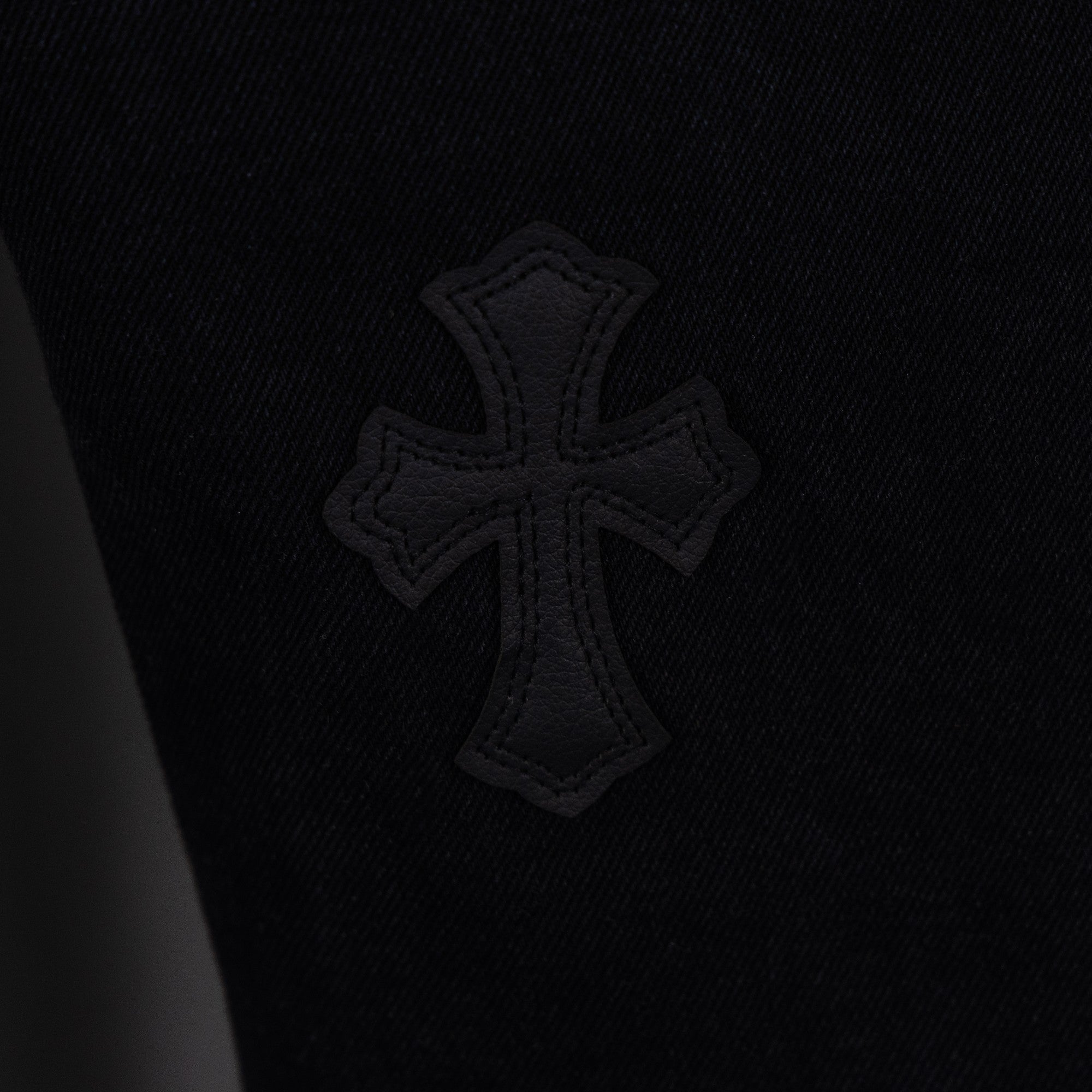 Black denim pants with embroidered cross emblem patch