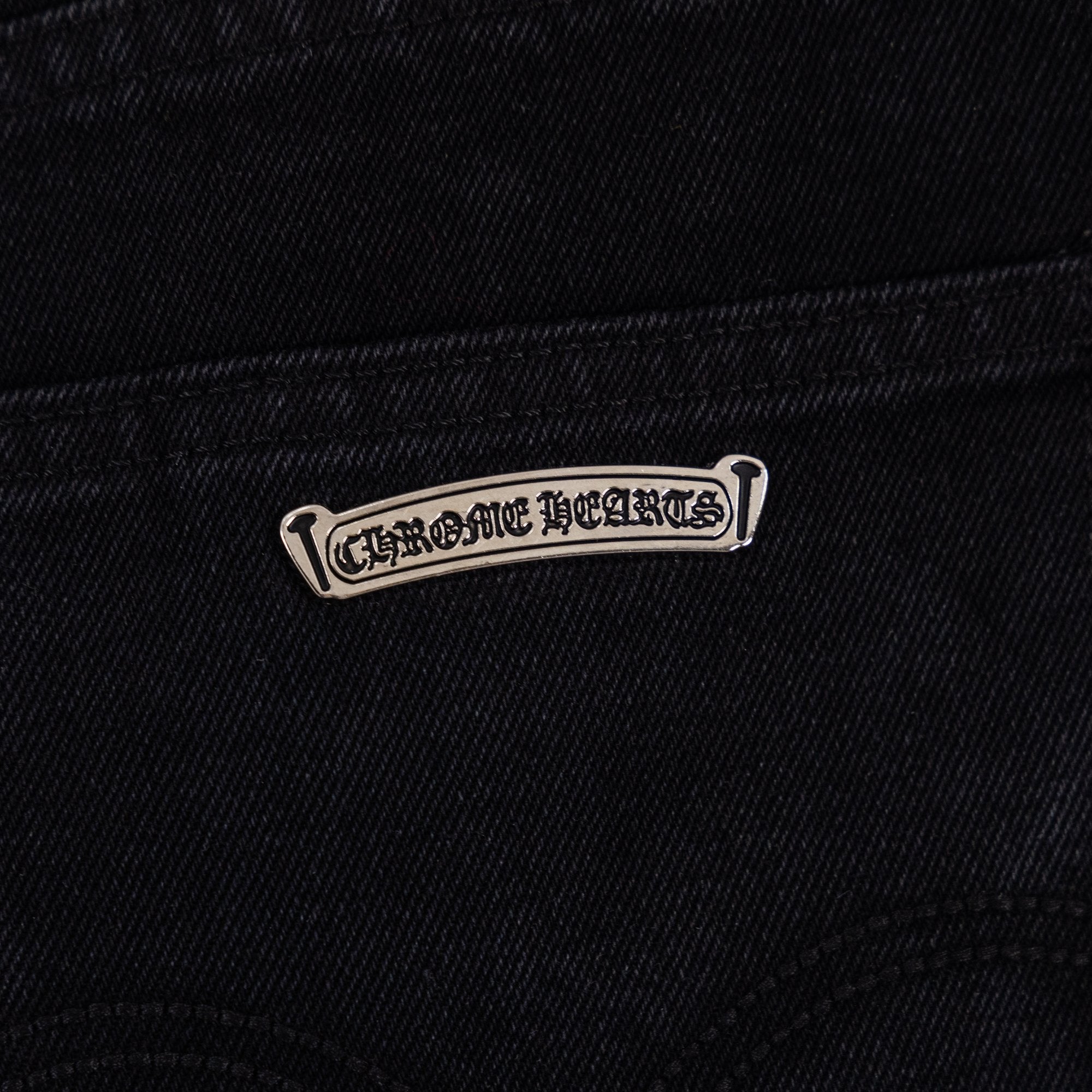 Black denim pants with stitched logo tab near the pocket