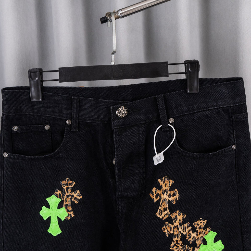 Black denim pants front view with tan and green cross embroidery detail
