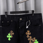 Black denim pants front view with tan and green cross embroidery detail