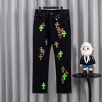 Black denim pants with green and tan cross embroidery on both legs