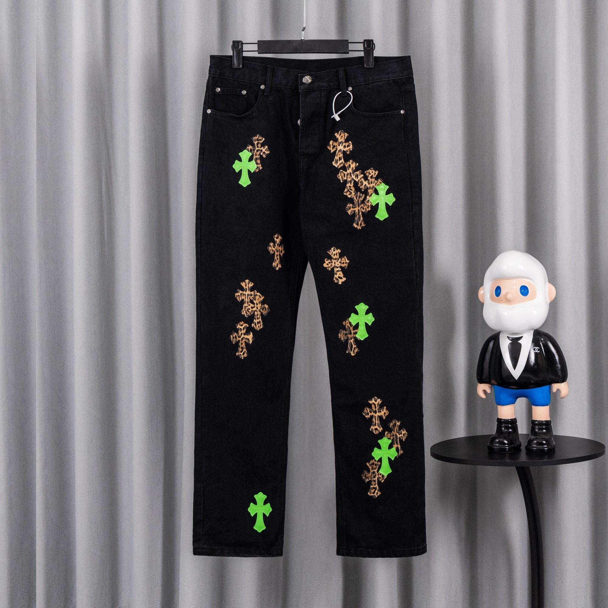 Black denim pants with green and tan cross embroidery on both legs